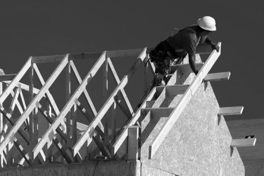 a carpenter building a house, working on roof joists