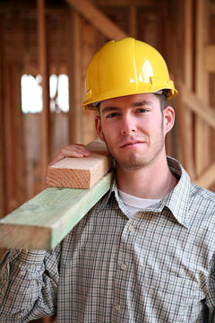a framing carpenter carrying two by four lumber